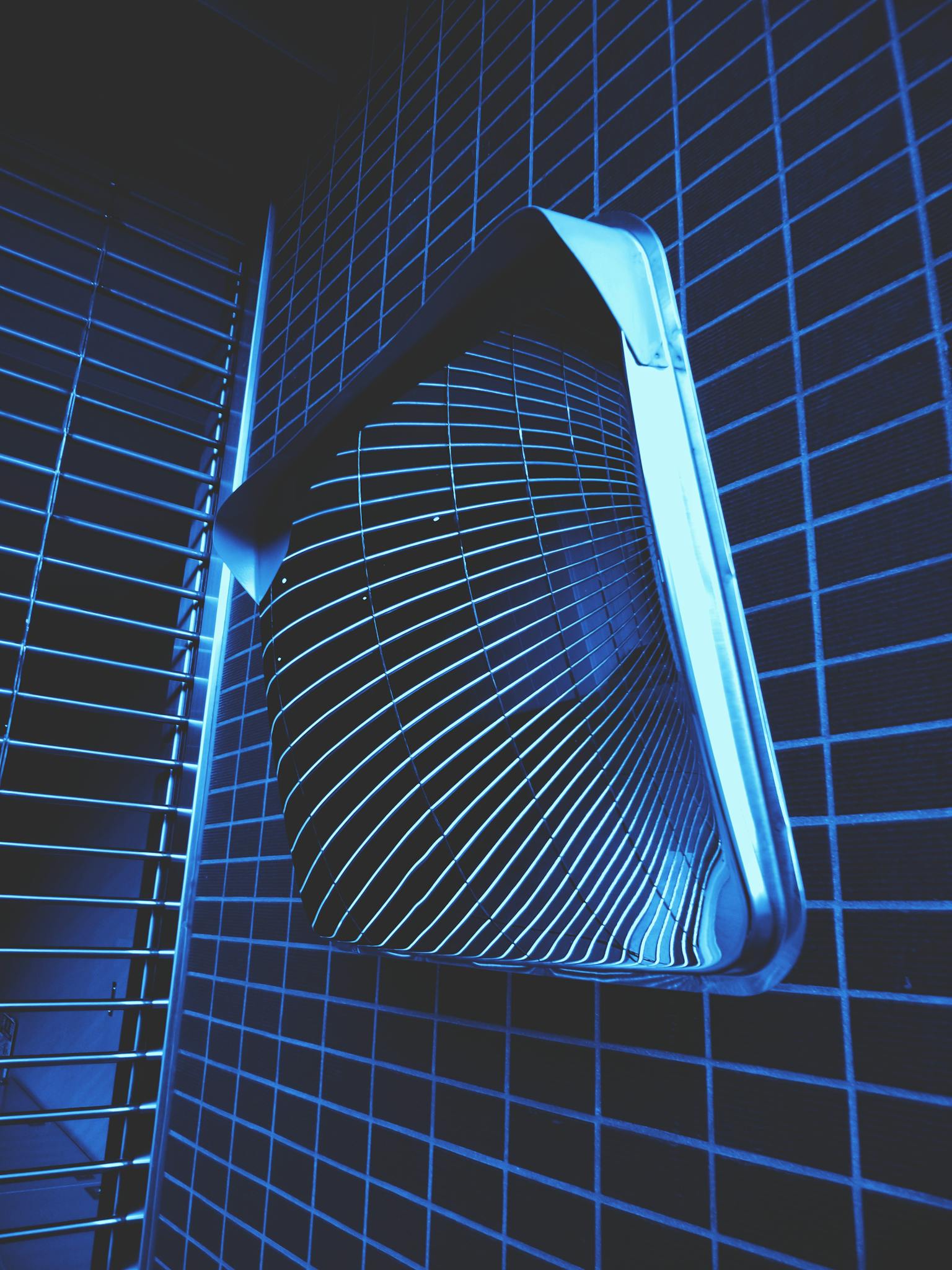 A contemporary bathroom fan with a sleek design in a modern, blue-toned setting.